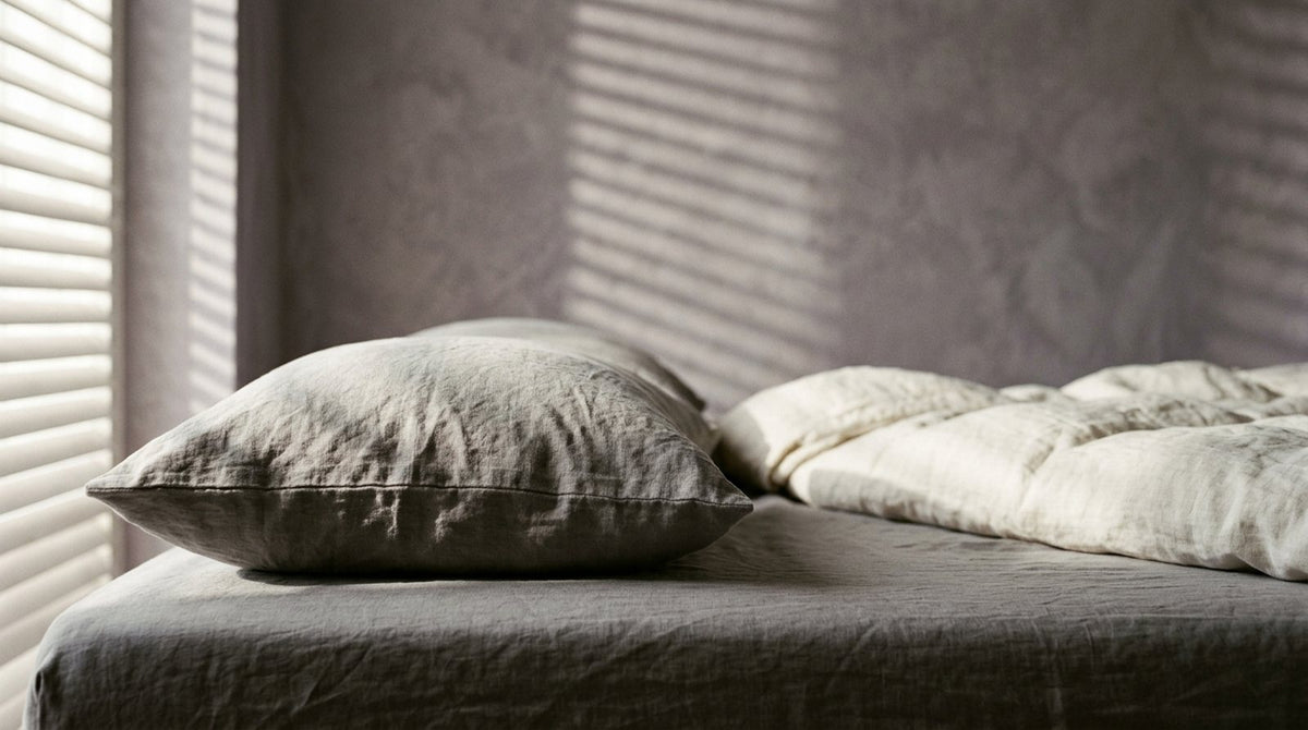 Almohada cervical de contorno en forma de mariposa sobre una cama con ropa de cama de lino claro