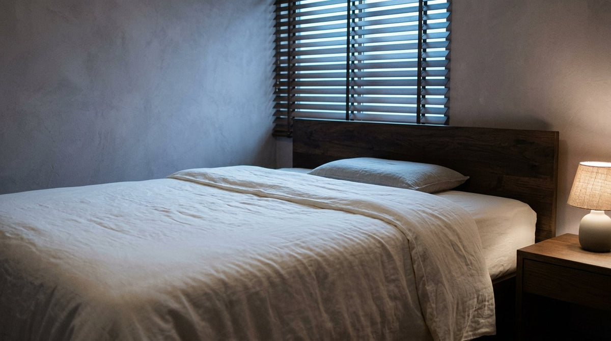 Cama hecha con ropa de cama de lino claro y una almohada baja apoyada en el cabecero