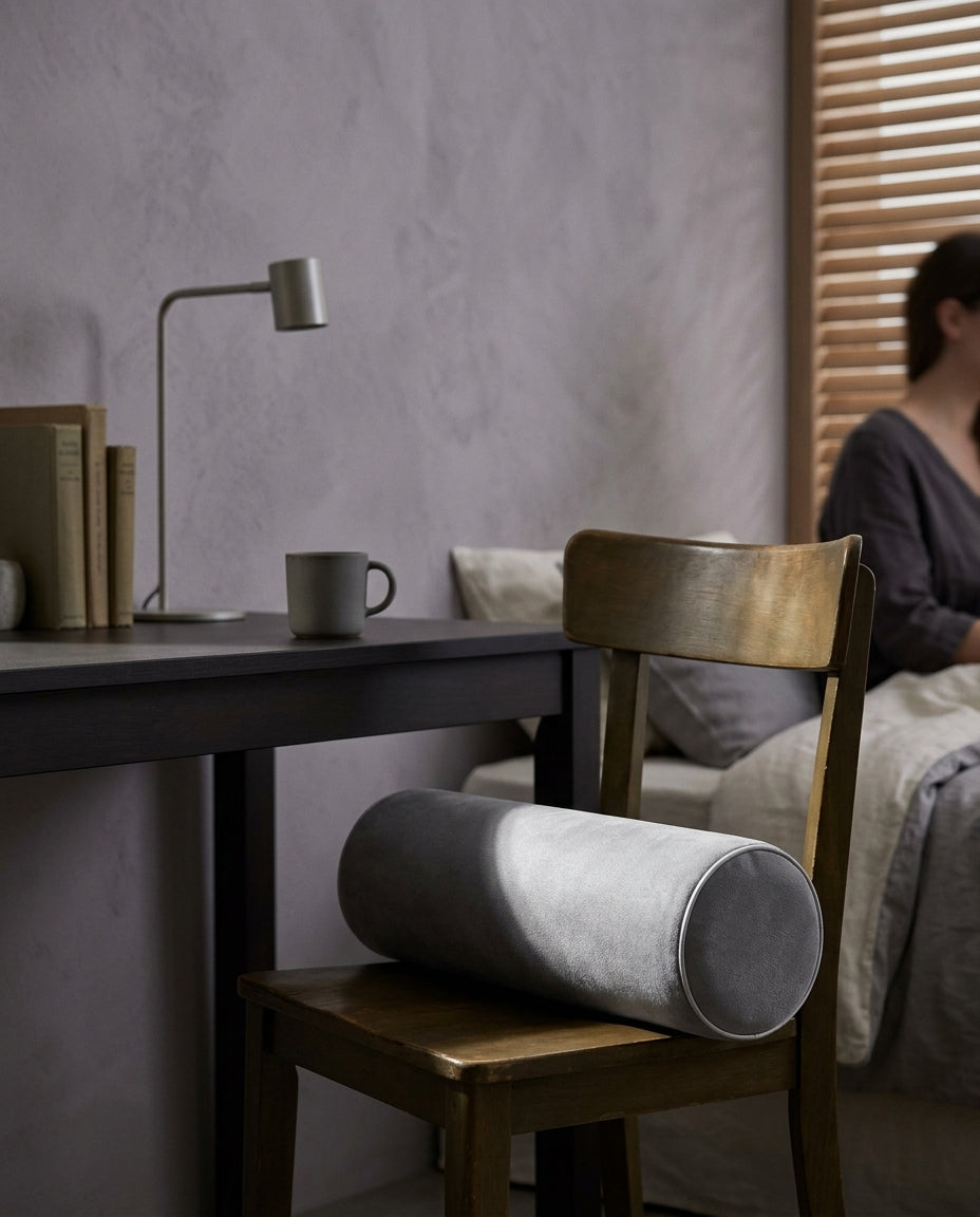 Cojín cilíndrico enrollable Rollo, en una silla de madera junto a un escritorio